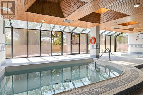 A large indoor swimming pool with a wooden ceiling and a glass wall.