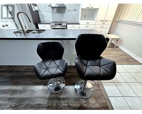 Two black leather chairs with metal legs in front of a kitchen counter.