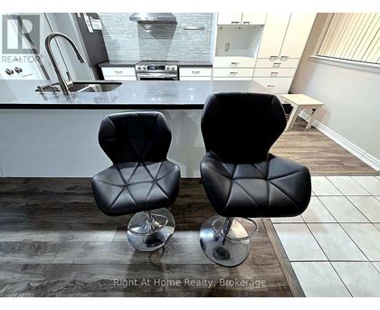 Two black leather chairs with metal legs in front of a kitchen counter.