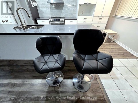 Two black leather chairs with metal legs in front of a kitchen counter.