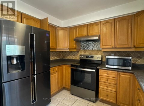 A kitchen with wooden cabinets and a black refrigerator.