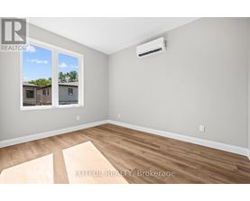 A room with a window showing a view of a house and a wall with a realtor logo.