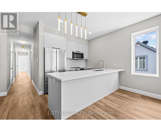 A modern kitchen with a white countertop and wooden flooring.