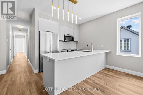 A modern kitchen with a white countertop and wooden flooring.