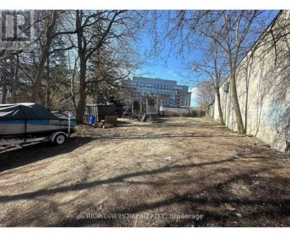 A dirt road with a trailer and a building in the background.