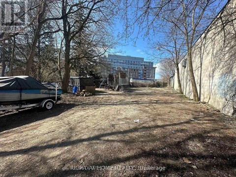 A dirt road with a trailer and a building in the background.