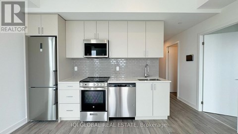 A modern kitchen with white cabinets and stainless steel appliances.
