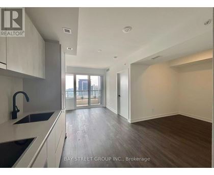 A spacious kitchen with a sink and a window overlooking the city.