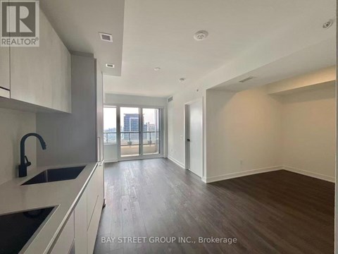 A spacious kitchen with a sink and a window overlooking the city.