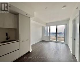 A well-lit, spacious apartment with a kitchen area and sliding glass doors leading to a balcony.
