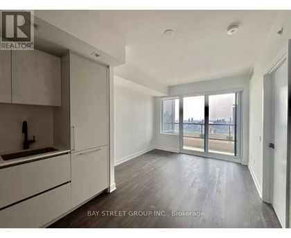 A well-lit, spacious apartment with a kitchen area and sliding glass doors leading to a balcony.