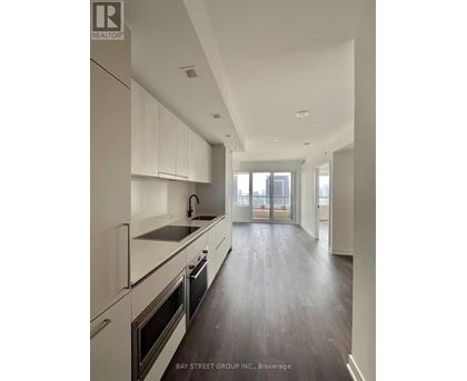 A modern kitchen with white appliances and wooden floors.