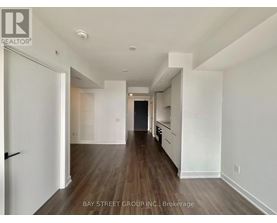 A spacious room with wooden floors and white walls, part of a Bay Street Group Inc. property.