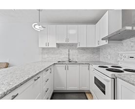 A kitchen with white cabinets and a marble countertop.