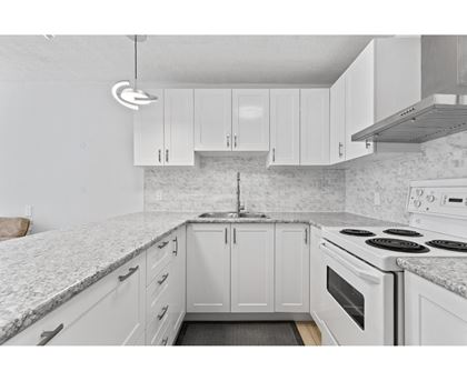 A kitchen with white cabinets and a marble countertop.