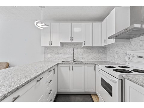 A kitchen with white cabinets and a marble countertop.