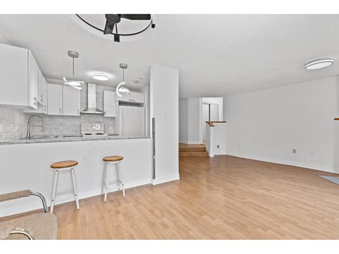 A kitchen with white cabinets and a bar stool.
