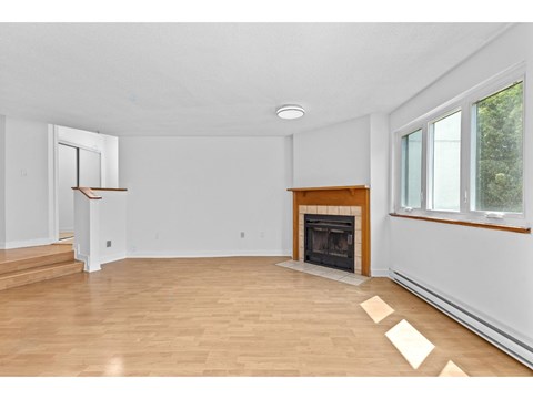 A living room with a fireplace and wooden floors.