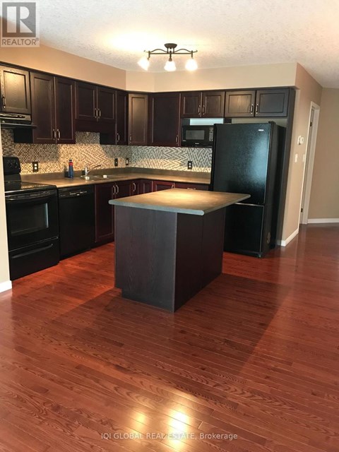 A kitchen with dark wood cabinets and a black refrigerator.