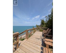 A wooden deck with chairs overlooking a beach.
