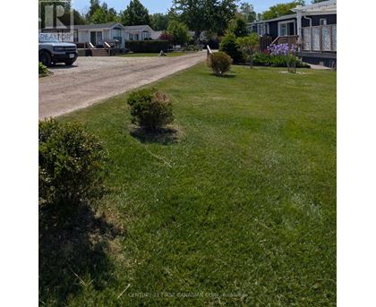 A grassy area with a sign that says "Century 21 First Canadian Corp. Brokerage".