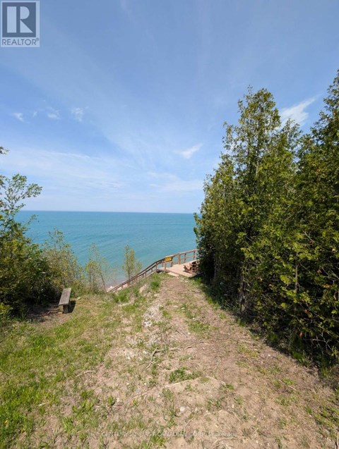 A view of a beach from a hill with a wooden walkway leading down to the water.