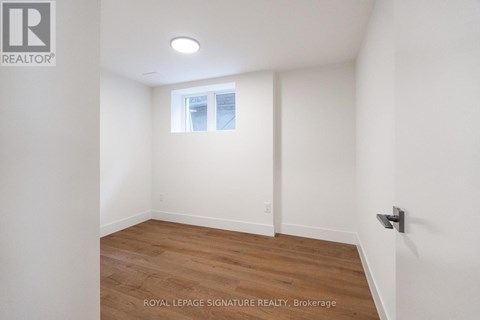 A white room with a wooden floor and a window.
