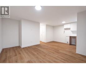 A room with wooden flooring and white walls, with a logo in the top left corner.