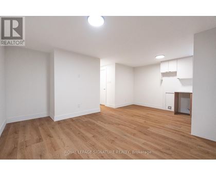 A room with wooden flooring and white walls, with a logo in the top left corner.
