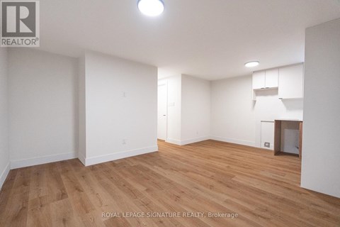 A room with wooden flooring and white walls, with a logo in the top left corner.