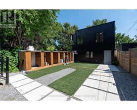 A modern black house with a gravel and grass yard.