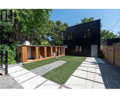 A modern black house with a gravel and grass yard.