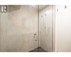 A bathroom with a glass shower door and a white door.