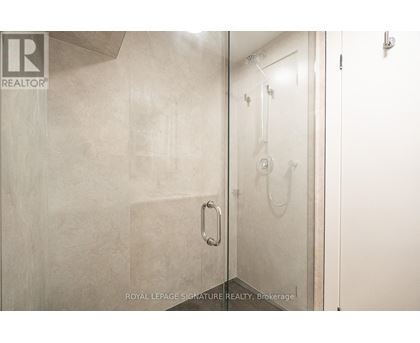 A bathroom with a glass shower door and a white door.