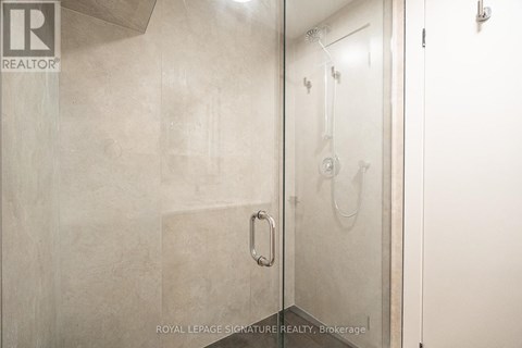 A bathroom with a glass shower door and a white door.