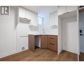 A white kitchen with wooden floors and cabinets.