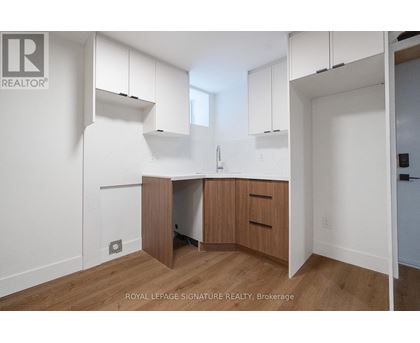 A white kitchen with wooden floors and cabinets.