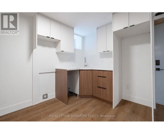 A white kitchen with wooden floors and cabinets.