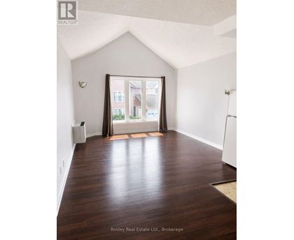 A room with wooden floors and a large window with a view of a building outside.