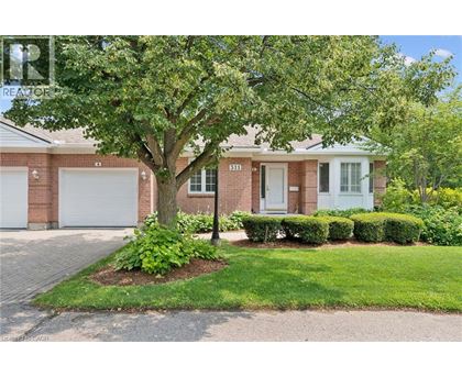 A tree in front of a brick house with a white garage door.