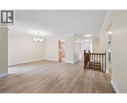 A spacious living room with wood flooring and a chandelier.