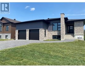 A modern house with a grey roof and a stone wall.