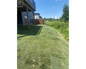 A grassy area with a house and a fence in the background.