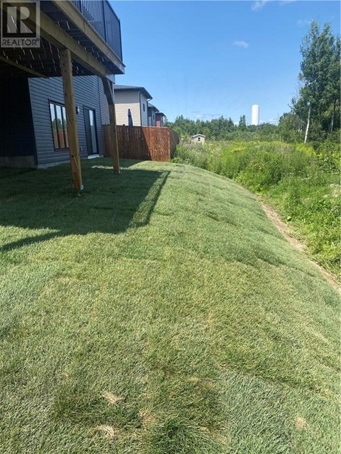 A grassy area with a house and a fence in the background.