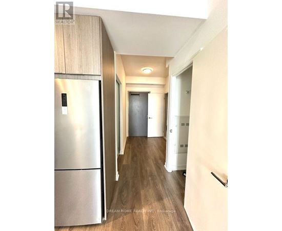 A modern kitchen with a stainless steel refrigerator and wooden flooring.