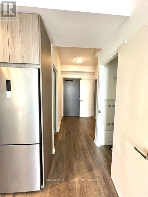 A modern kitchen with a stainless steel refrigerator and wooden flooring.