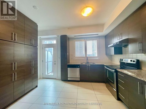 A kitchen with dark wood cabinets and a white dishwasher.
