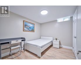 A bedroom with a bed, chair, and painting on the wall.