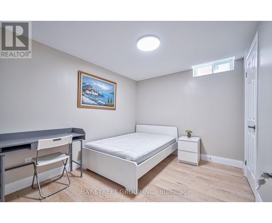 A bedroom with a bed, chair, and painting on the wall.