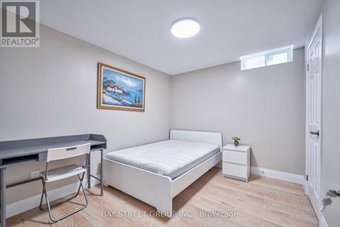 A bedroom with a bed, chair, and painting on the wall.